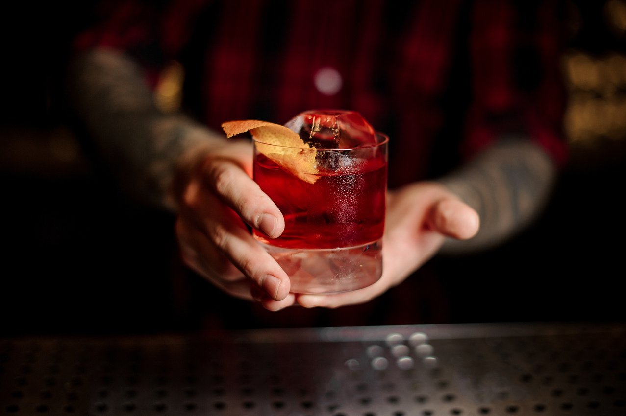 Mixologist holding a glass of strong fresh whiskey cocktail