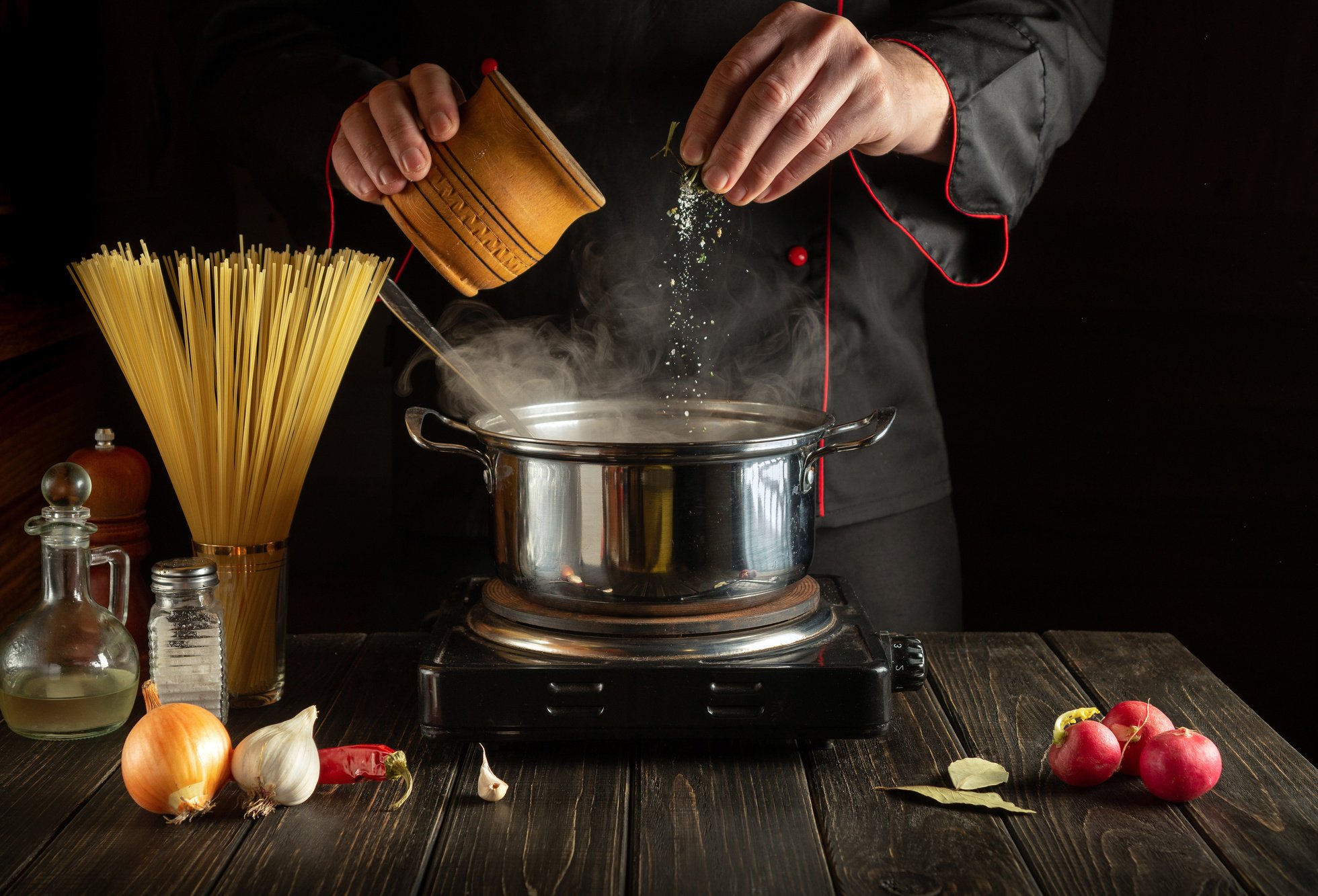 Experienced chef adds salt to Stock pot of boiling water. Cookin