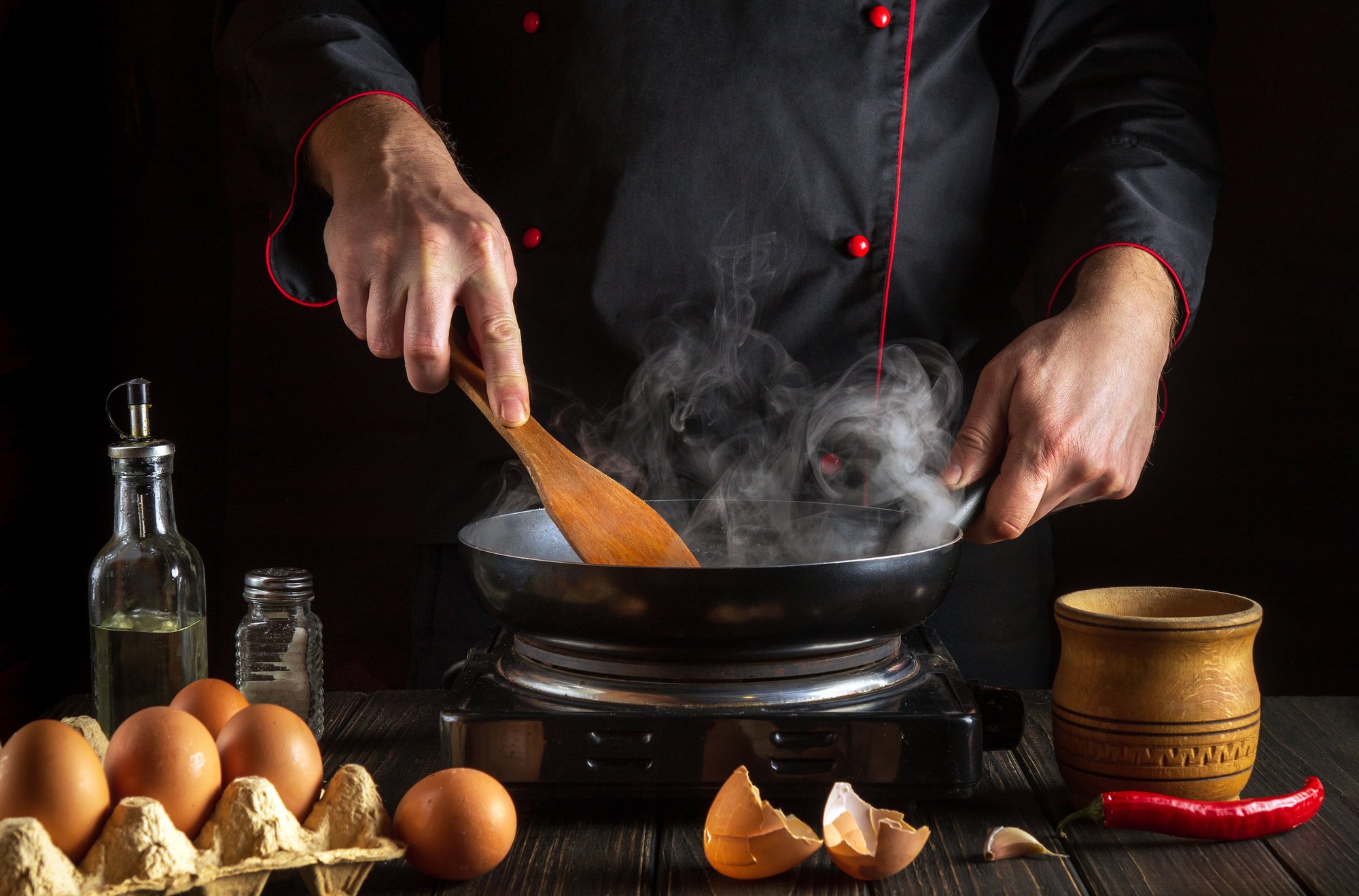 Professional chef frying eggs in a frying pan. Cooking an omelet